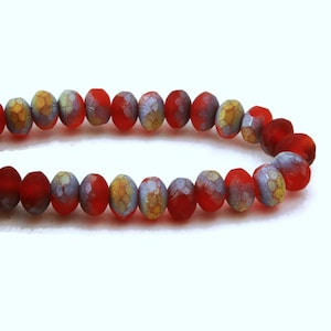 May include: A strand of red glass beads with a textured, iridescent finish. The beads have a subtle pattern of gold and silver.