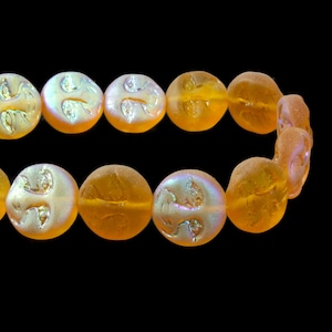 May include: A strand of orange glass beads with an iridescent finish. Each bead has a raised design of a stylized bird.