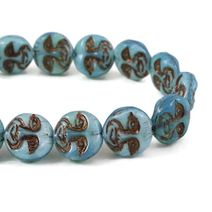 May include: A strand of blue glass beads with a gold-colored design. The beads are oval-shaped and have a slightly iridescent finish.