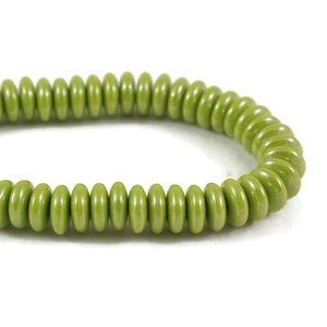 May include: A green beaded bracelet made of round, flat beads. The beads are arranged in a spiral pattern.