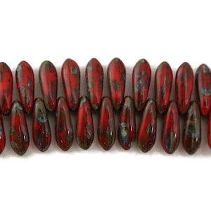 May include: A strand of red and green glass beads with a speckled pattern. The beads are shaped like teardrops and are strung together on a clear thread.