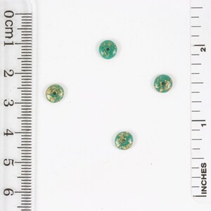 May include: Four green and gold round beads with a hole in the center. The beads are about 1/2 inch in diameter.