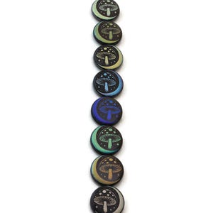 May include: A vertical arrangement of seven round wooden buttons. Each button features a crescent moon and a mushroom design. The color scheme varies from light blue to dark blue, with yellow and green accents. The buttons are on a white background.