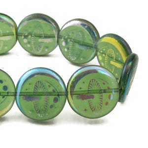 May include: A strand of green glass beads with iridescent accents. Each bead features a mushroom design.