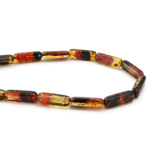 May include: A strand of colorful, rectangular glass beads. The beads are a mix of red, orange, yellow, and black.