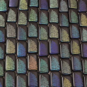 May include: A collection of small, rectangular tiles with a fern design in various shades of blue, green, and yellow. The tiles are arranged in a grid pattern.