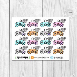 Puede incluir: Una hoja de 12 pegatinas de mandos de juego de colores con el texto "GAME ON" en cada una. Los mandos son de varios colores, incluyendo rosa, azul, gris y naranja.