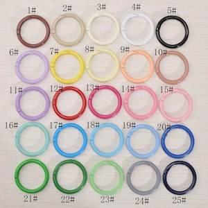 Puede incluir: Una colección de 25 cierres de resorte redondos de metal de colores. Los cierres están disponibles en varios colores, incluyendo marrón, beige, amarillo, blanco, negro, morado, rojo, rosa, azul claro, verde y azul marino. Cada cierre tiene un número del 1 al 25.