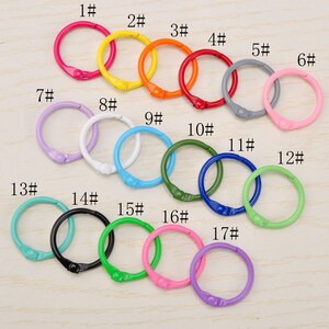 May include: Seventeen circular metal binder rings in various colours, including pink, yellow, orange, red, grey, light pink, lavender, white, light blue, dark green, blue, light green, teal, black, green, magenta, and purple, each labelled 1# through 17#.