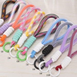 May include: A selection of ten colourful wrist lanyards. Each lanyard has a looped rope design in various colours, including orange, pink, blue, and purple. They have a ring for keys or other small items. The lanyards are numbered 1 to 10.