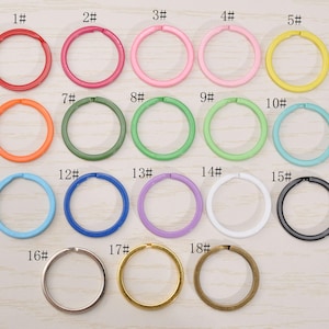 May include: A collection of eighteen key rings in various colors, including red, pink, yellow, orange, green, blue, purple, white, silver, gold, and black. Each ring is numbered from 1 to 18.