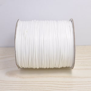 May include: A spool of white cord, wound tightly and ready for crafting projects.