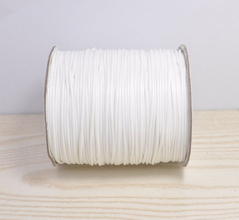 May include: A spool of white cord, wound tightly and ready for crafting projects.