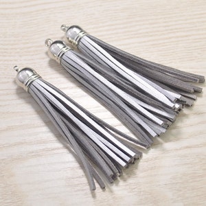 Könnte beinhalten: Drei graue Lederquasten mit silbernen Metallkappen. Die Quasten sind etwa 12,7 cm lang.
