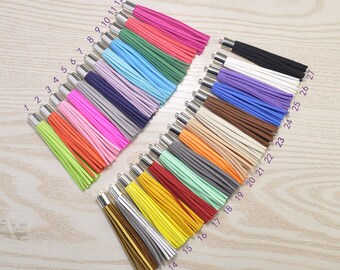 May include: A collection of colorful tassels with silver-toned caps. The tassels are arranged in rows, showcasing a variety of hues including pink, green, orange, and yellow. Each tassel is numbered, indicating a selection of colors.