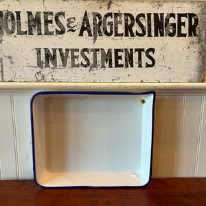 May include: A white enamel baking dish with a blue rim. The dish is empty and ready to be used.