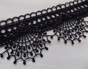 May include: Black lace trim with a scalloped edge and delicate beading. The lace has a delicate, intricate design.