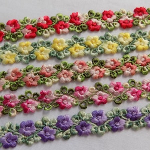 May include: Five rows of floral trim with different colored flowers. The trim is made of embroidered fabric and features small flowers in shades of red, yellow, pink, and purple.