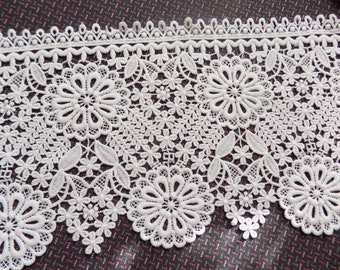 May include: White lace trim with a delicate floral pattern. The trim features a scalloped edge and intricate details.