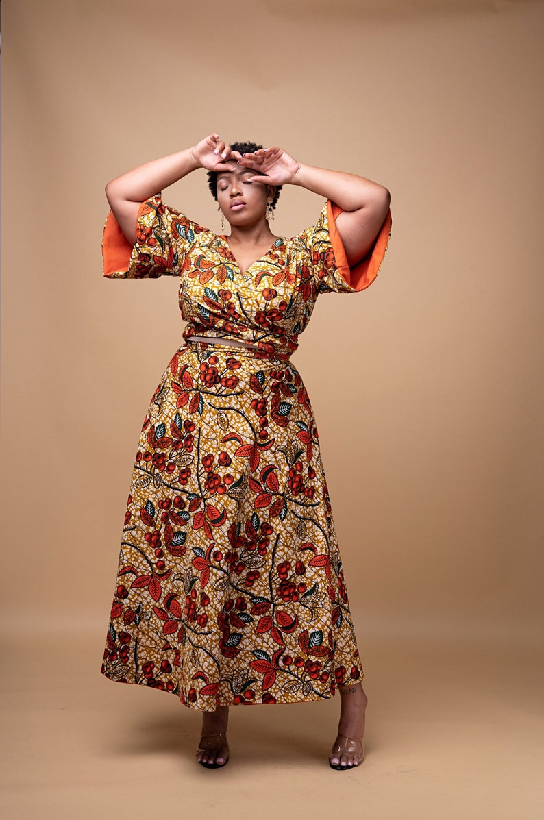 Black Woman Wearing Orange African Print Reversible Wrap Skirt and Wrap Blouse from Besida