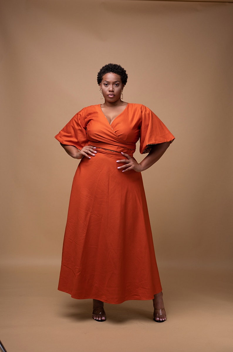 Black Woman Wearing Orange African Print Reversible Wrap Skirt and Wrap Blouse from Besida