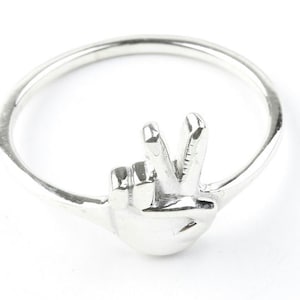 May include: A silver ring with a peace sign design. The ring is made of metal and has a smooth finish.