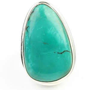 May include: A turquoise ring with a silver setting. The turquoise is a teardrop shape and has a smooth, polished finish.