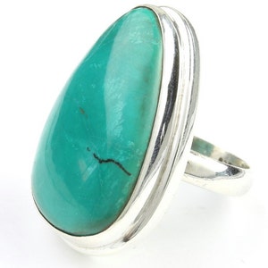 May include: A turquoise ring with a silver band. The turquoise stone is teardrop shaped and has a dark vein running through it.