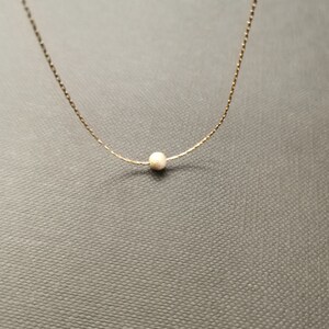 Peut inclure: Un collier délicat en chaîne dorée avec un seul petit pendentif en perle ronde.