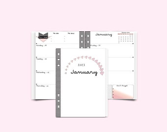 Könnte beinhalten: Ein weißer Planer mit einem schwarz-weiß gestreiften Rücken. Der Einband zeigt ein pinkfarbenes Herzdesign und den Text "Januar 2023".