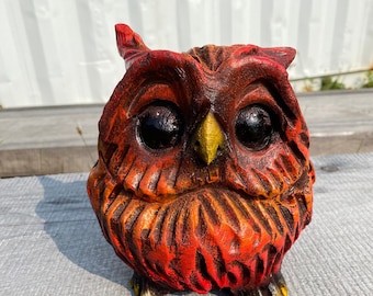 May include: A carved wooden owl figurine with a vibrant red, orange, and yellow color scheme. The owl has large, dark eyes and a yellow beak. The figurine is approximately 6 inches tall and has a detailed, textured surface.
