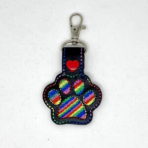 May include: A black leather keychain with a rainbow striped paw print and a red heart.