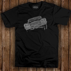 May include: Black t-shirt featuring a detailed, white line drawing of a classic car. The car is angled, showcasing its front grill and headlights. The shirt has a crew neck and short sleeves. The brand name "LOLOL" is printed on the back of the neck.