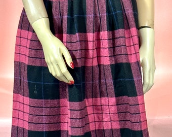 May include: A vintage pink and black plaid skirt. The skirt features a pleated design and a high waist. The plaid pattern is a bold combination of pink and black squares with thin blue and purple lines. The skirt is knee-length.