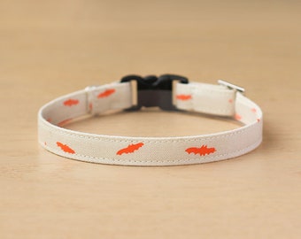 May include: A white cotton dog collar with a black buckle and orange bat silhouettes.