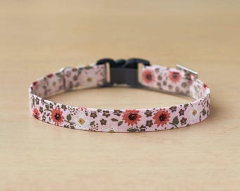 May include: A pink and brown floral patterned dog collar with a black plastic buckle.