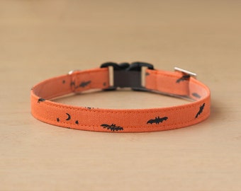 May include: Orange fabric pet collar with black bat and crescent moon pattern.