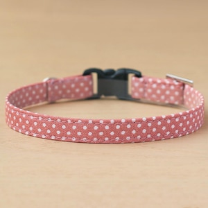 May include: A pink and white polka dot dog collar with a black plastic buckle and a silver metal D-ring.