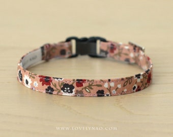May include: A pink floral patterned cat collar with a black plastic buckle. The collar is approximately 1 inch wide.