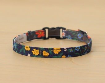 May include: A blue and floral patterned cat collar with a black plastic buckle.