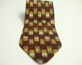 May include: A patterned necktie with a repeating geometric design. The tie features a dark reddish-brown background with a pattern of squares in shades of gold, gray, and white. The tie is made of a textured fabric.