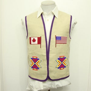 May include: Beige vest with purple trim and embroidered designs. Features the flags of Canada and the United States. The vest has two colourful geometric patterns near the bottom. Worn over a white collared shirt.
