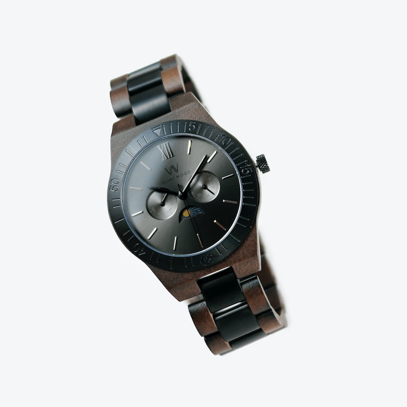 May include: A black and brown wooden wristwatch with a black face and silver hands. The watch has a moon phase complication and a date window. The watch is made by the brand "Wood & Watch".
