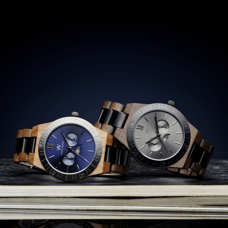 May include: Two wooden wristwatches with black and brown bands. The watch faces are silver and blue with Roman numeral markings and moon phase indicators.
