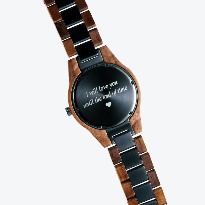 May include: A wooden and black metal wristwatch with a black face and an engraved message that reads "I will love you until the end of time" with a small heart symbol.