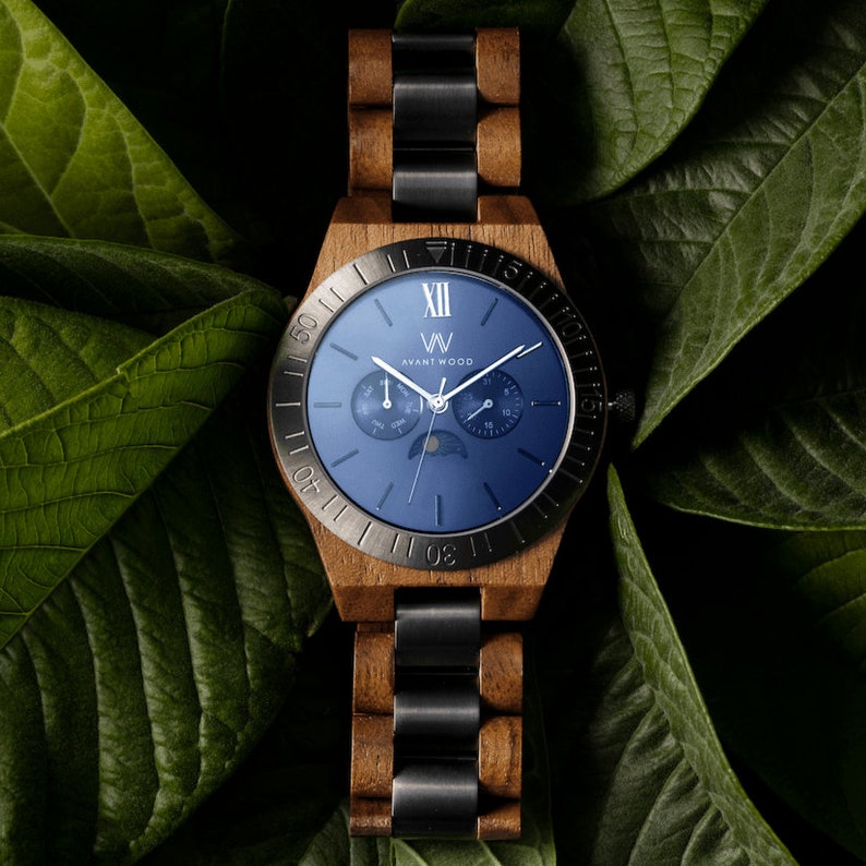May include: A blue-faced wristwatch with a wooden band and black metal accents. The watch face features a moon phase indicator, a date window, and the text "VV Avant Wood".