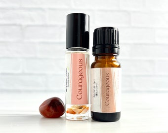 May include: Two glass bottles with black caps and labels that say "Courageous" in white text. The bottles are on a white surface with a red carnelian stone.