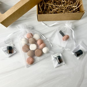 May include: A set of 10 round, scented diffusers in a variety of colors, including white, beige, and pink. The diffusers are in a white organza bag with a small bottle of essential oil.