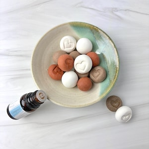 Puede incluir: Juego de tres tazas de cerámica con acabado mate moteado. Las tazas son de color crema, gris claro y gris oscuro. Cada taza tiene un diseño simple y minimalista.