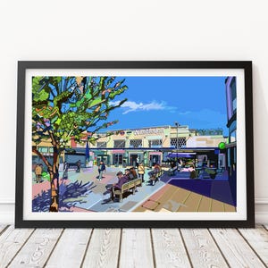 May include: A framed art print of Wimbledon station, rendered in a colorful, stylized illustration. The artwork depicts the station's facade, people, and surrounding trees under a bright blue sky. The word "Wimbledon" is visible on the building.